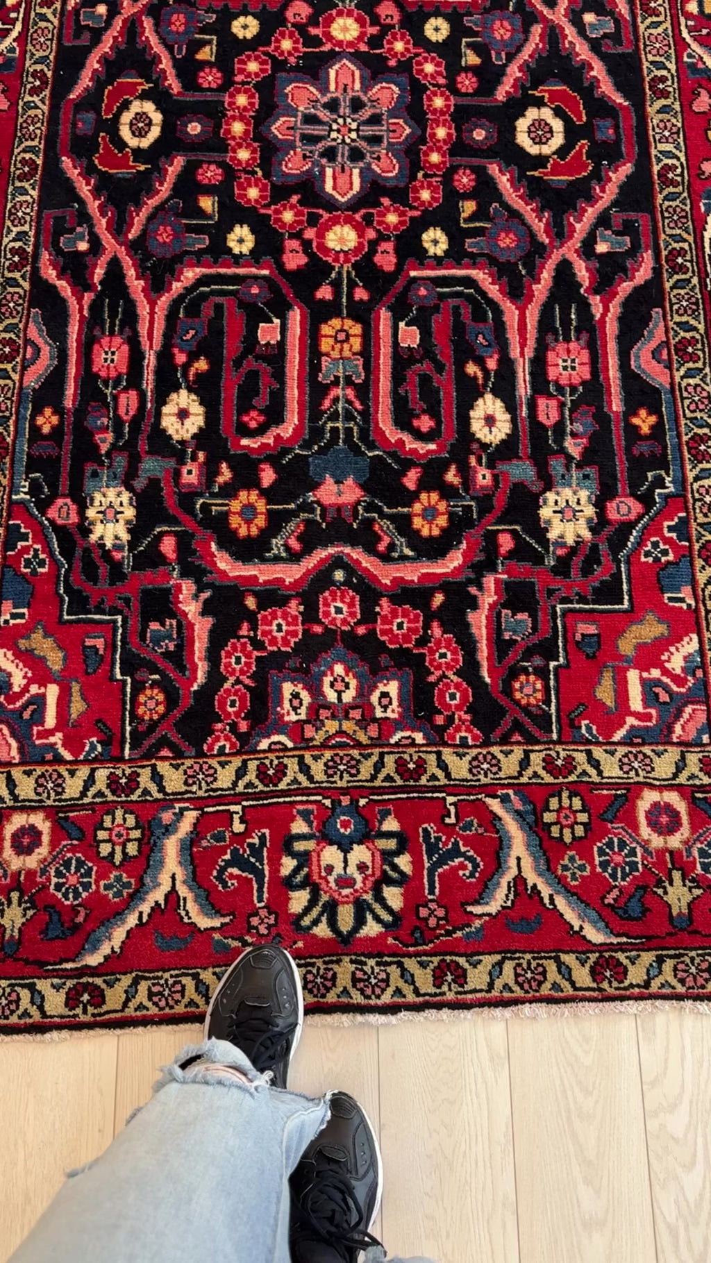 Close-up of Hand-Knotted Vintage Wool Area Rug – 8' 2" x 4' 10" with person’s feet for scale, highlighting detailed floral motifs and rich colors.