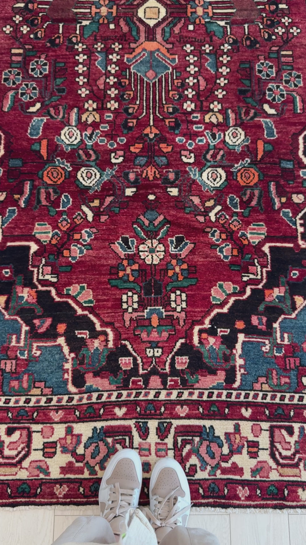 Close-up top-down view of Hand-Knotted Collectible Persian Malayer Red Floral Vintage Rug with shoes for scale, emphasizing rich red tones and floral motifs.