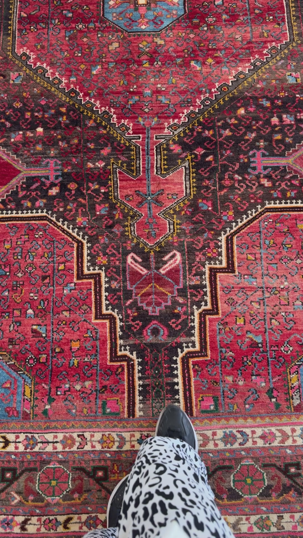 Detailed view of vintage wool area rug's central design with vibrant red and black tones, showcasing fine hand-knotting craftsmanship.