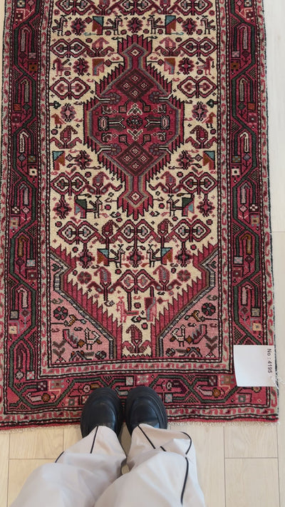 Close-up of Hand-Knotted Vintage Wool Runner Rug – 10' 11" x 2' 7" showing fine red and ivory motifs with person’s feet for scale.
