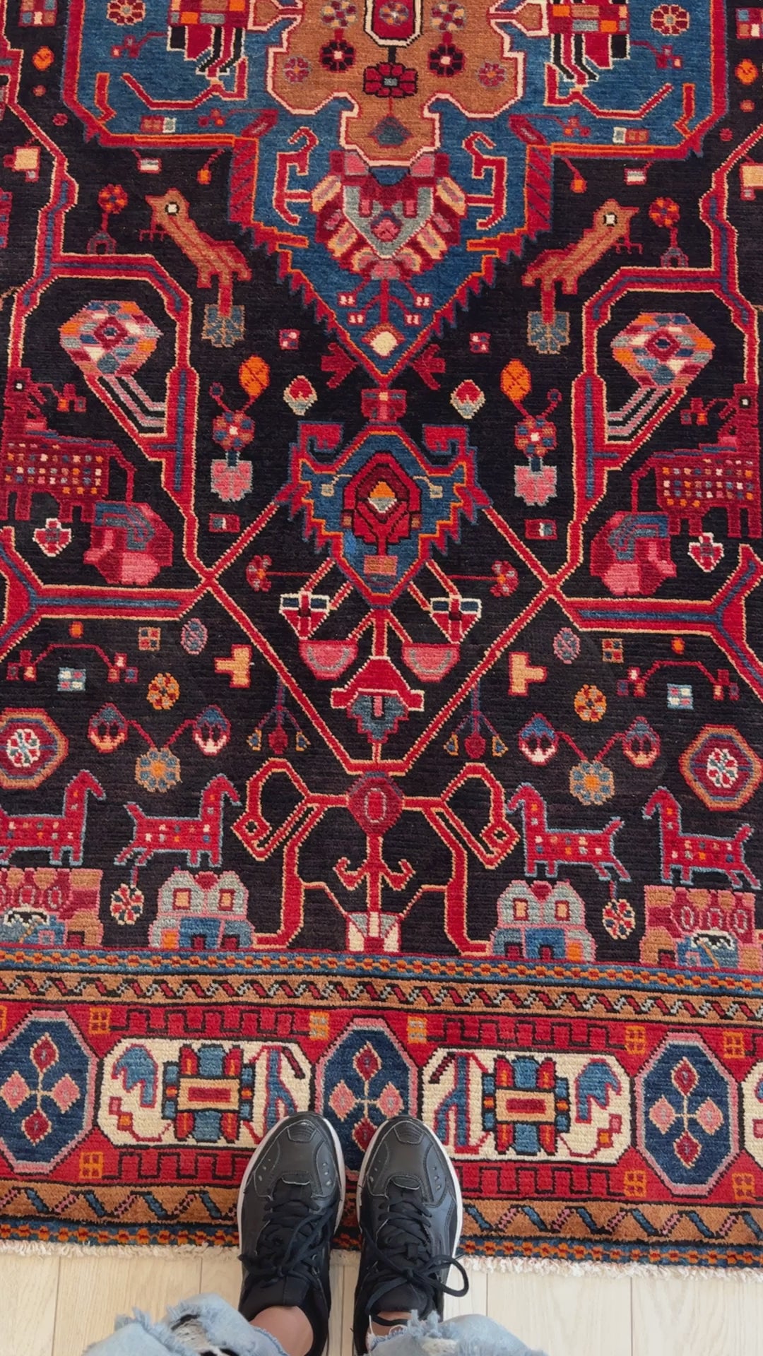 Close-up of Hand-Knotted Vintage Wool Area Rug – 9' 5" x 5' 6" highlighting detailed red and blue motifs with black background and border accents.