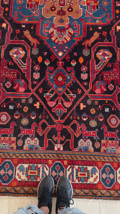 Close-up of Hand-Knotted Vintage Wool Area Rug – 9' 5" x 5' 6" highlighting detailed red and blue motifs with black background and border accents.