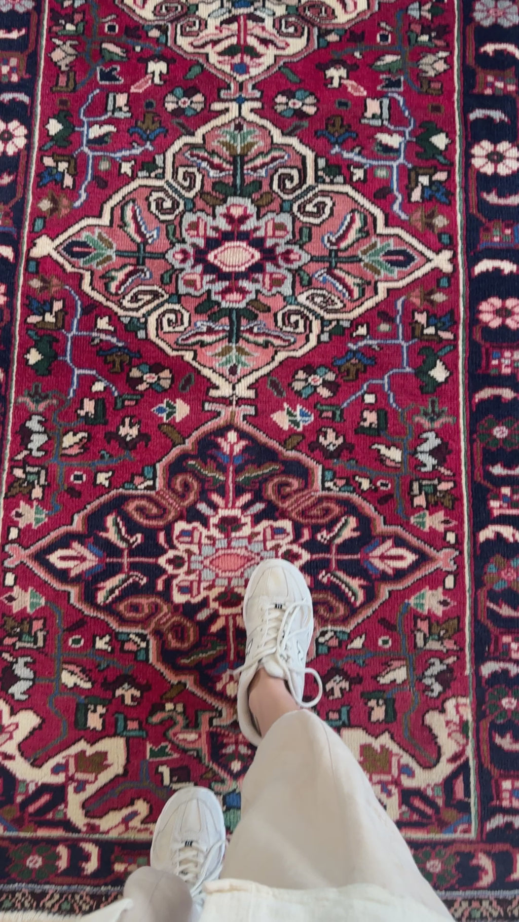 Close-up of hand-knotted vintage wool runner rug in red and navy, showcasing detailed floral motifs and texture underfoot.