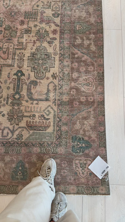 Close-up of corner detail on hand-knotted vintage wool rug, 12'7" x 9'1", highlighting faded tribal motifs and soft pastel colors.