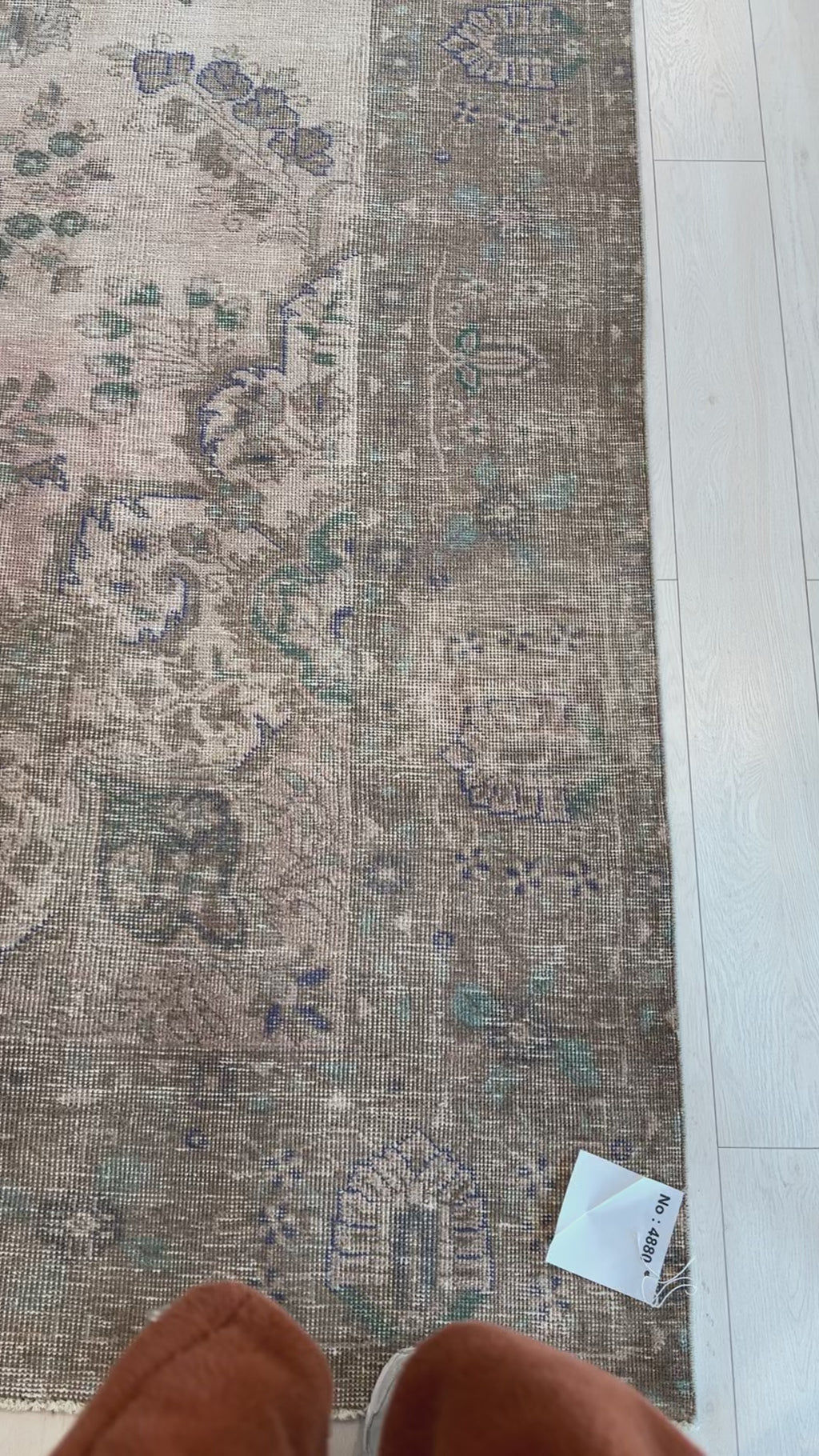 Close-up of faded border detail on hand-knotted vintage wool area rug, showcasing intricate floral motifs in muted green and purple hues.