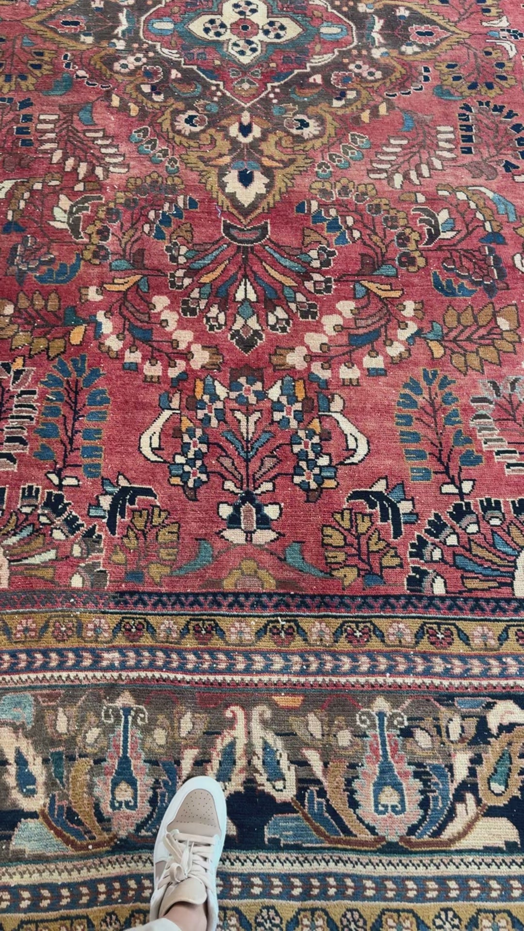 Close-up of the central floral motif and border of the hand-knotted vintage wool rug, emphasizing its rich red and navy color palette.