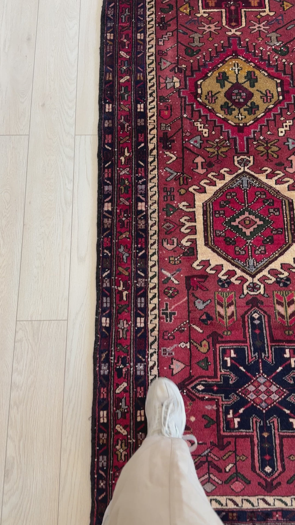 Close-up of Hand-Knotted Vintage Wool Runner Rug – 11' 2" x 3' 1" showing intricate border and tribal design with foot for scale on light wood floor.