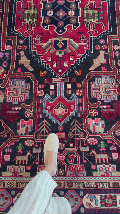 Close-up of the Hand-Knotted Vintage Wool Area Rug – 10' 2" x 5' 6" highlighting detailed animal and floral motifs in vibrant red and navy hues.